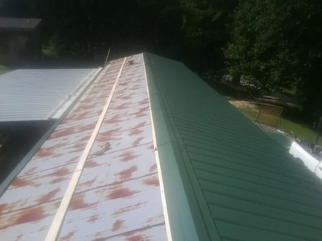 Old rusted panels beside newly installed green metal roofing — Wind Damage Roof Repair by Roofing Brothers in Tall Timbers