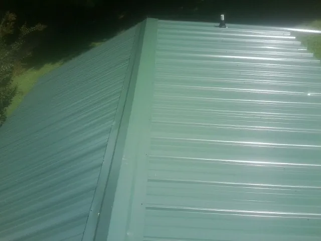 New green metal panels meeting at the ridge of a roof — Flat Roof Repair work by our crew in Tall Timbers