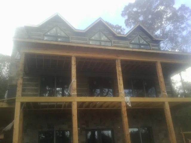 Dormers and porch framing on a large log home under construction — Roof Coating work by our crew in Tall Timbers