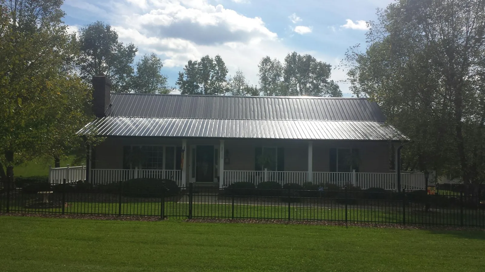 Gray metal roof on a brick ranch with a full width front porch — Gutter Guard Installation work by our crew in Tall Timbers