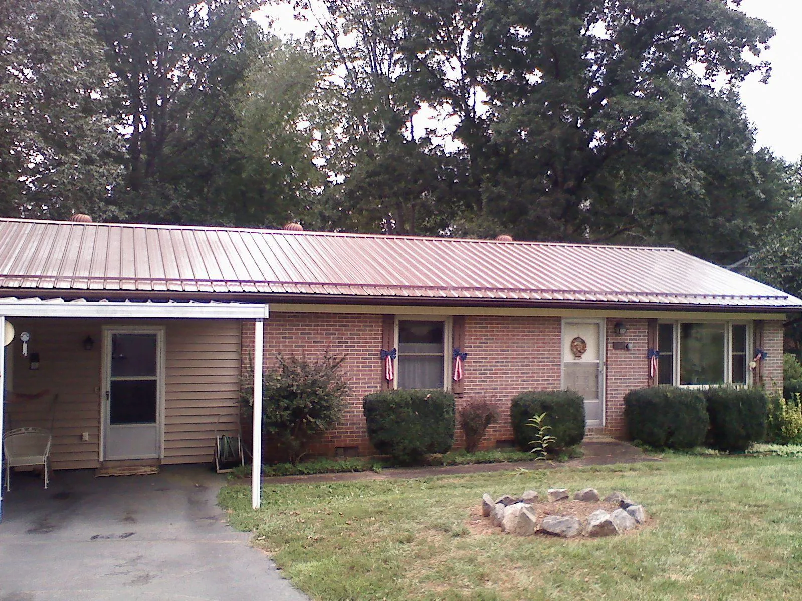 Bronze metal roof and carport on a brick ranch home — Roof Repair work by our crew in Tall Timbers