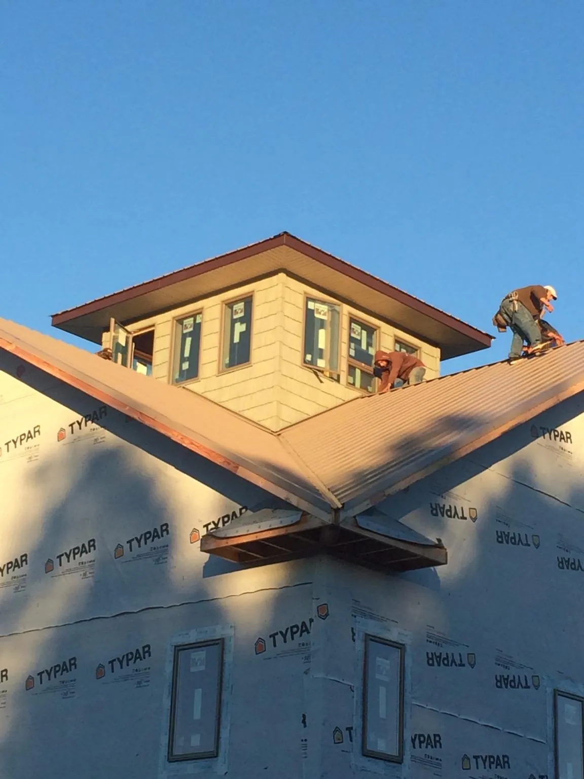 Roofers working around a rooftop cupola on a new metal roof at sunset — Roof Waterproofing in Tall Timbers by Roofing Brothers